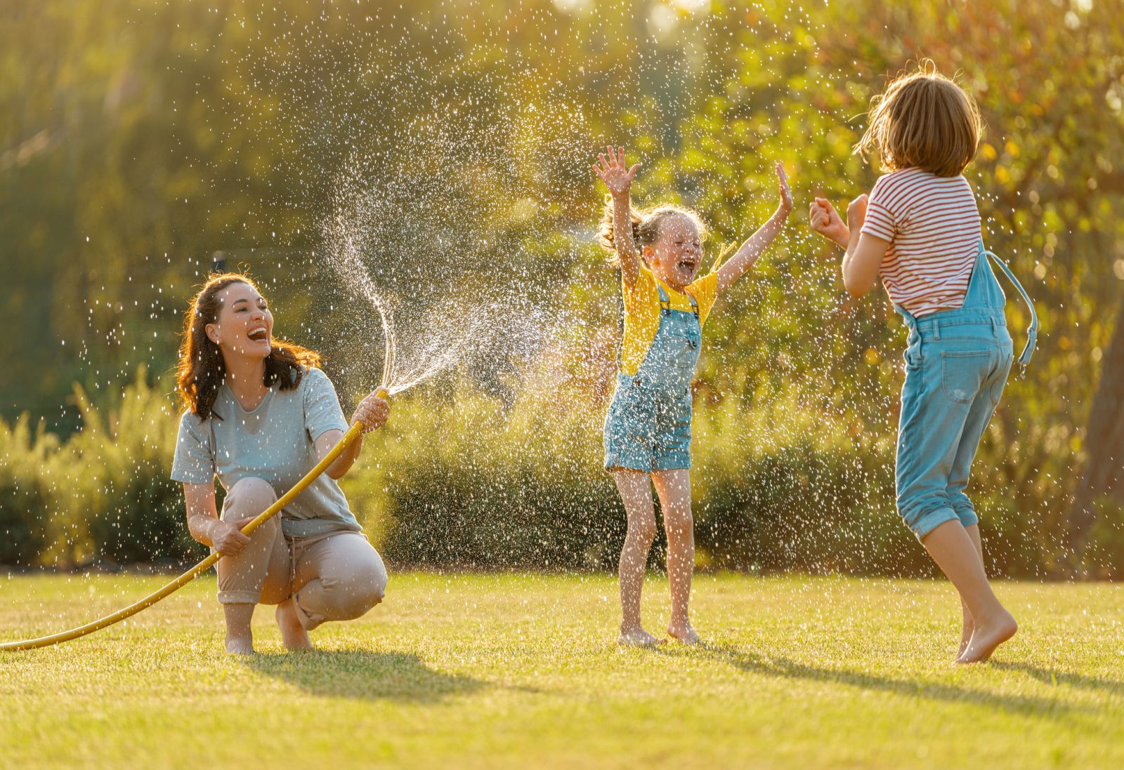 Two kids and a woman enjoying on a lawn